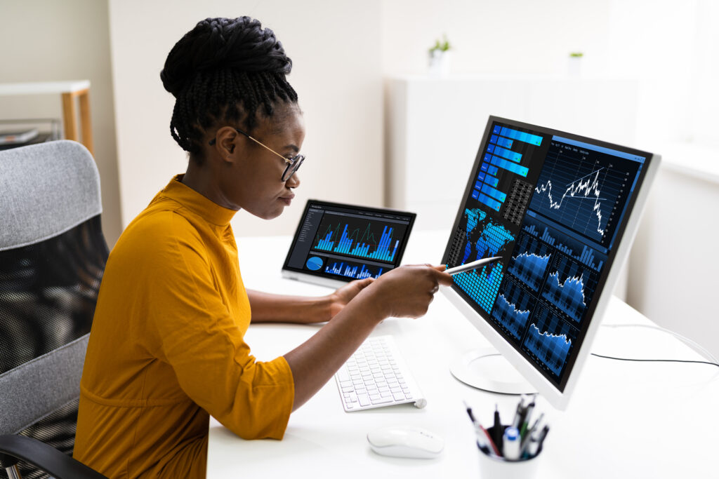 Image of young African American businesswoman monitoring analytics and graphs on a computer