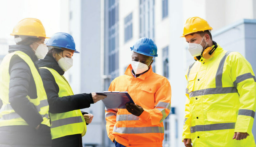 stock image of health and safety workers in hard hats inspecting the outside of a workplace