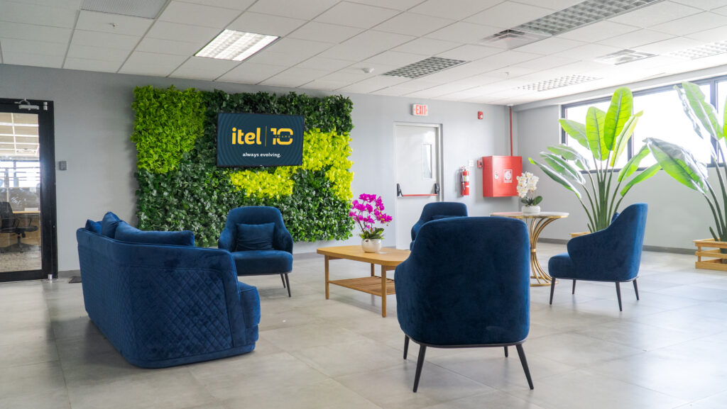 Image of the interior of itel's Chalmers building in Jamaica. Outside the contact center production floors are informal gathering spaces, created by clusters of plush, velvety furnishings in natural colors that reflect the vibrant Caribbean landscape outside. With flatscreens nested inside verdant botanical walls